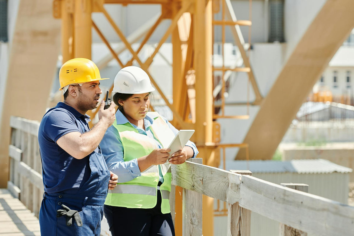 Two contractors in hard hats using a tablet on a job site